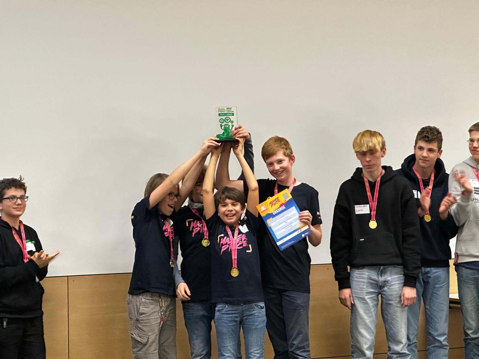 Das Team hält den Masterpiece Forschungspokal auf der Bühne hoch