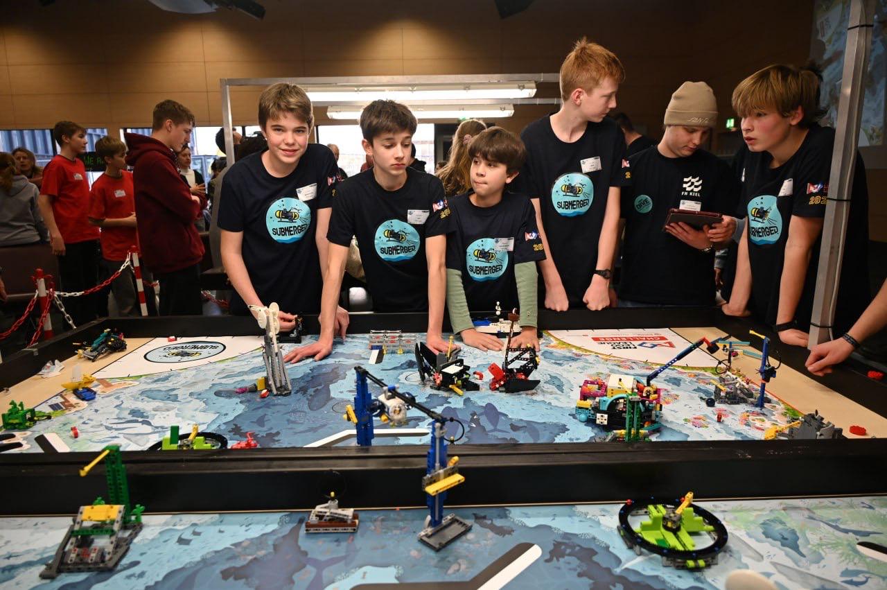 Teammitglieder mit dem Submerged-Roboter am Wettbewerbstisch